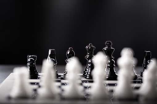 Closeup of part of a chess game with focus on the black set and white set in the foreground out of focus