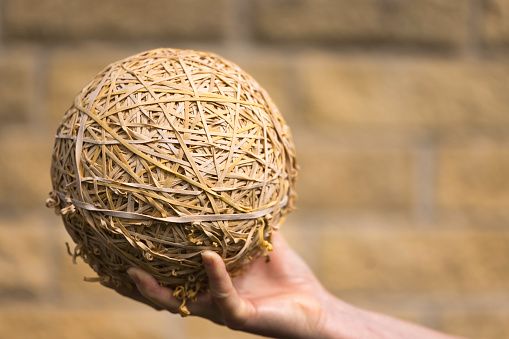 Large ball of elastic bands, collected over many years and beginning to perish. Their owner wears an anorak, train-spotting is his only hobby and he is a very lonely person.