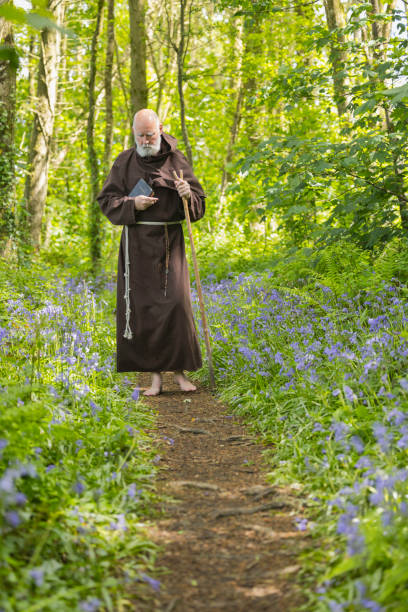 Elderly monk walking in the woods Monk in contemplation as he walks through a bluebell wood in Spring. bluebell photos stock pictures, royalty-free photos & images