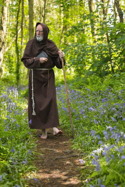 Elderly monk walking in the woods Monk in contemplation as he walks through a bluebell wood in Spring. bluebell photos stock pictures, royalty-free photos & images
