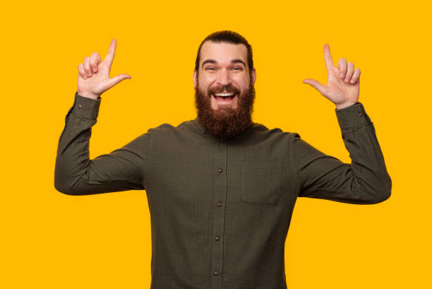 istock Portrait of a bearded man pointing up with both hands at the copy space. 1398298345