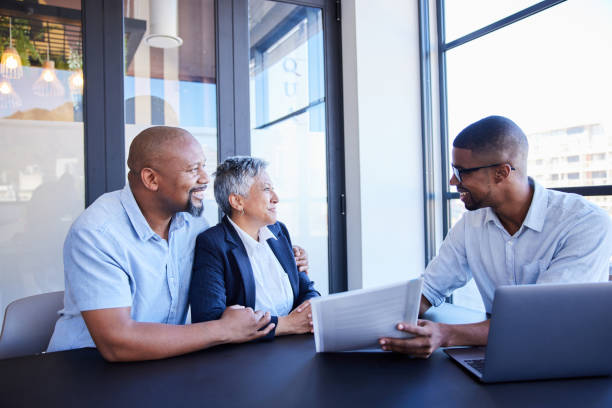 Smiling financial advisor discussing paperwork with a mature couple in an office