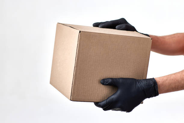 istock Delivery man hand in gloves holding package box 1398301245