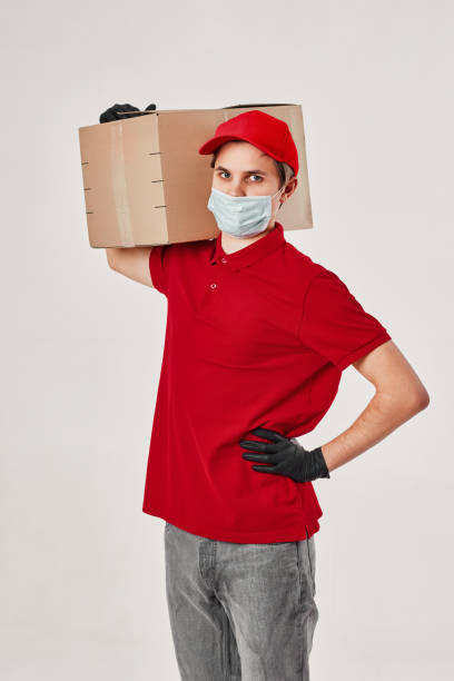 istock Delivery man employee in red cap face mask, empty cardboard box 1398301251