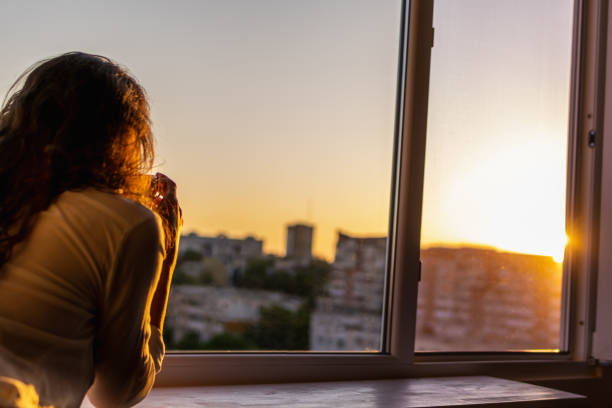 istock Woman watching the sunset from the window 1398301386