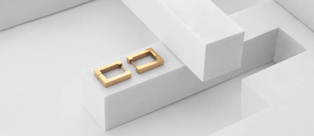 istock Panoramic shot of golden rectangular earrings pair on geometric white background 1398306442
