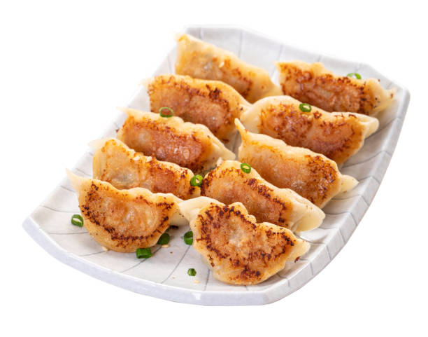 Pan-fried gyoza dumpling jiaozi in a plate isolated on white background.