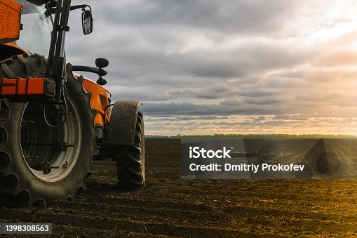 istock A tractor in the field on the background of uncultivated land. Copy space. 1398308563