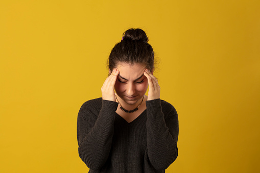 Photo portrait of serious and worried girl wearing striped t-shirt isolated on yellow background
