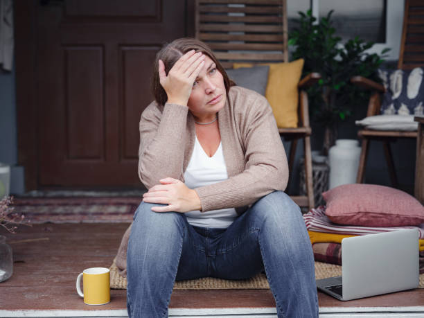 middle aged depressed woman sitting on porch. stock photo