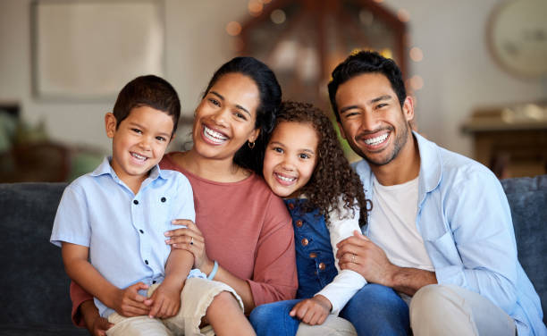 porträt einer lächelnden gemischtrassigen familie, die zusammen auf dem sofa zu hause entspannt. sorglos liebende hispanische eltern, die sich mit süßen kleinen kindern und töchtern verbinden. glückliche kinder, die zeit mit mama und papa verbringen - family child portrait little girls stock-fotos und bilder