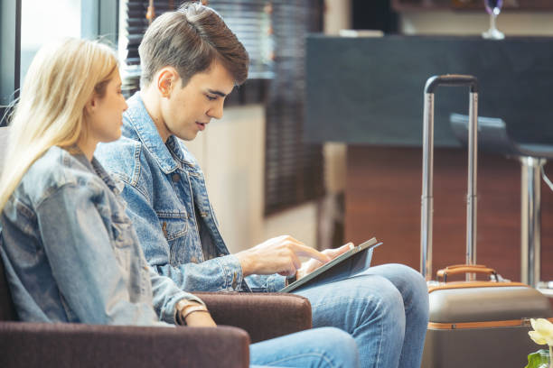 istock A couple sits in the hotel lobby, looking at a tablet computer. 1398312942