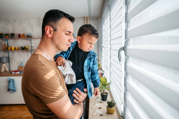 istock Father Holding His Child While Looking Out The Window 1398314637