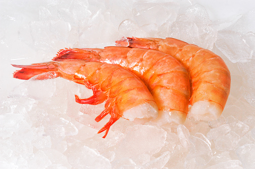 Close-up of raw shrimp on ice on display for sale.