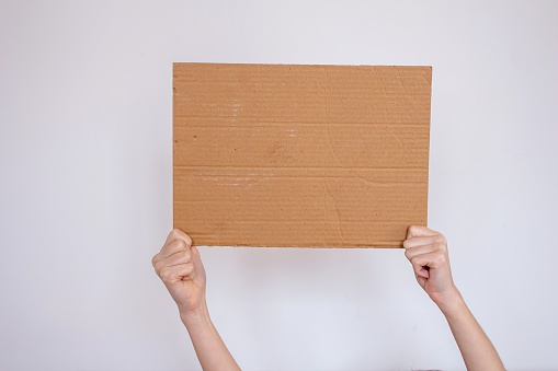 Woman holding blank cardboard box isolated on white background. Woman protesting something. Copy space on cardboard box.