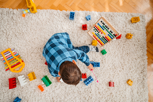 Toddler playing with toys on the floor at home by himself.