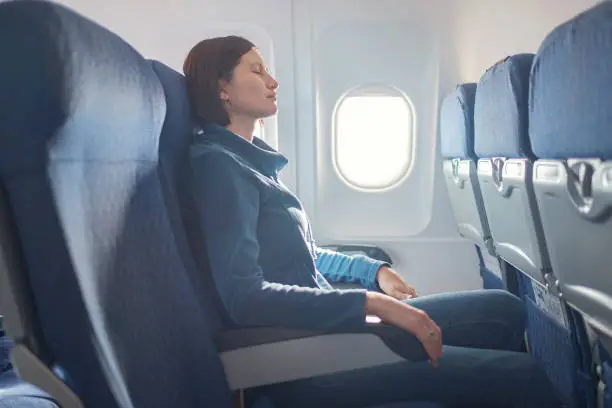 Photo of Young beautiful woman sitting at window of plane during the flight