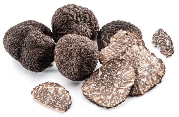 Photo of Black winter truffles and truffle slices on white background. The most famous of the trufflez.