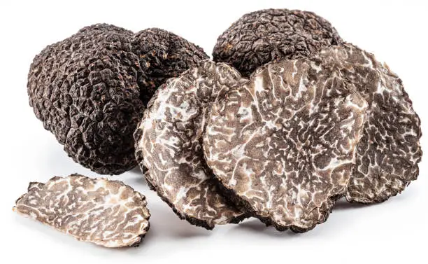 Photo of Black winter truffles and truffle slices on white background. The most famous of the trufflez.