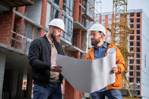 Man discussing building plan with architect at construction site. stock photo