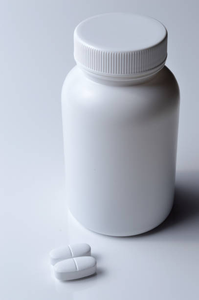 istock white plastic medicine jar and two white pills. light background. 1398319730