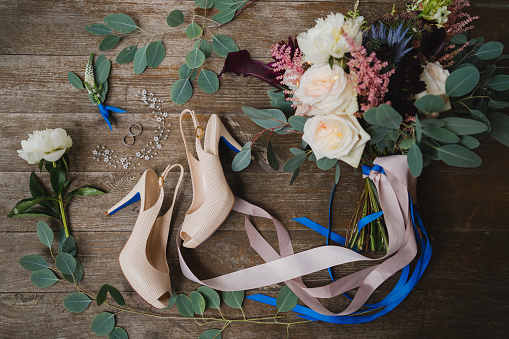 Ramo con cintas de seda, zapatos clásicos femeninos, boutonniere, anillos de boda y anillo de compromiso sobre fondo de madera natural. photo