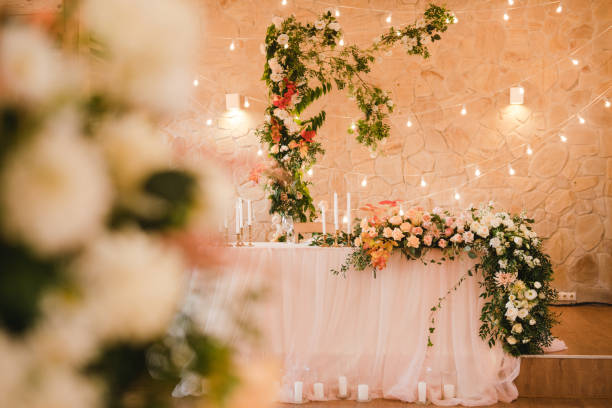 istock Table setting at the wedding reception. Floral compositions with beautiful flowers and greenery, candles, laying and plates on a decorated table. 1398322104