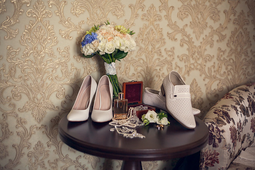 Wedding details and Preparing: bride's bouquet, white shoes, perfume bottle, necklace in a jewelry box, groom's boutonniere.