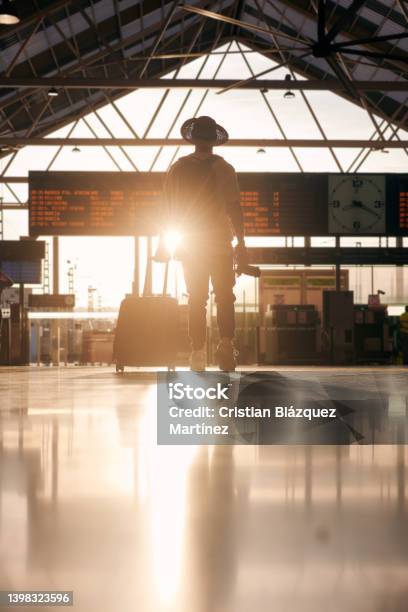 Silhouette Of A Man Wearing A Hat And Carrying A Suitcase Looking At A Destination Travel Panel Stock Photo - Download Image Now