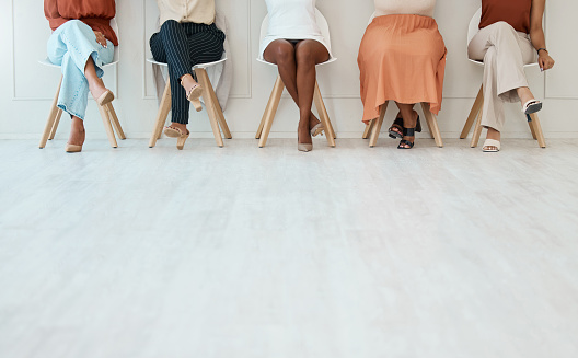 Grupo de cinco empresarias sentadas en sillas contra una pared en una oficina en el trabajo. Piernas de empresarios sentados en sillas en una fila juntos en el trabajo photo