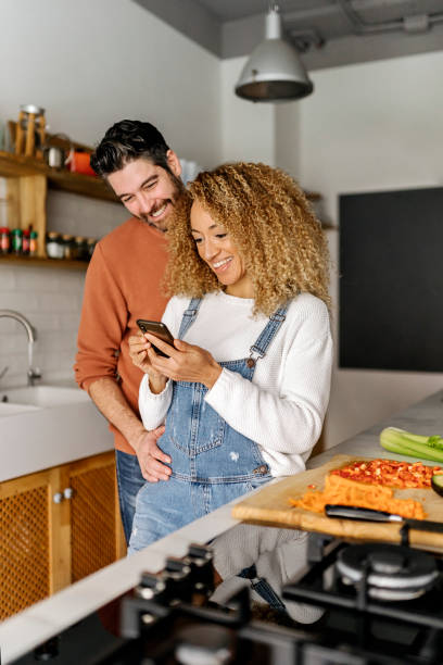 istock Couple looking at a smartphone in kitchen. 1398325886