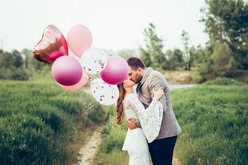 Loving bride and groom are kissing on meadow