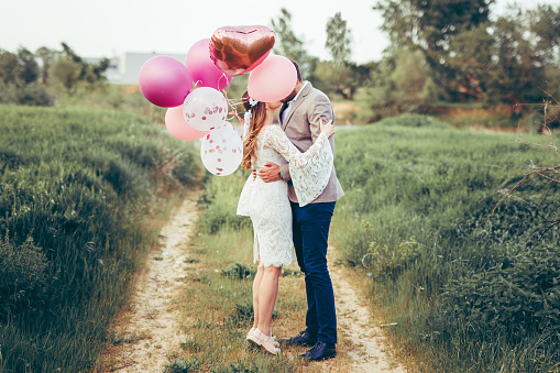 Bride and groom are kissing behind a balloons