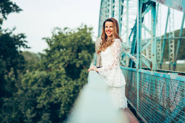 Happy bride on wedding day on bridge enjoys sunset