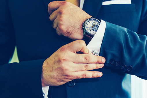 Elegant man correcting his cufflinks and sleeve.