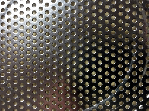 Perforated silver colored metal texture background