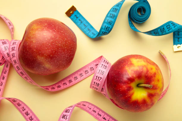 istock Diet concept with apples and measuring tapes, on a beige background. 1398330835