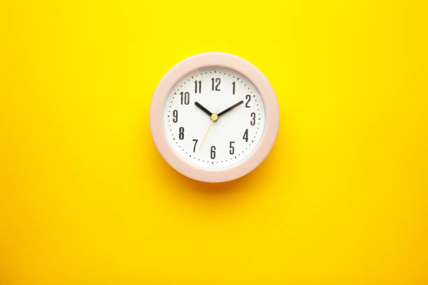 istock Pink clock on yellow background. Top view. 1398330878