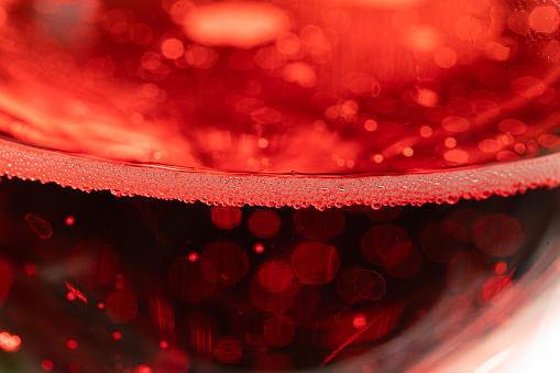 macro view of a transparent glass full of a red sparkling beverage full of microscopic bubbles