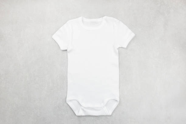 il modello bianco della neonata o del body del ragazzo giaceva piatto sullo sfondo grigio del cemento. modello di tutine di design, modello di presentazione stampato. vista dall'alto. - onesie foto e immagini stock