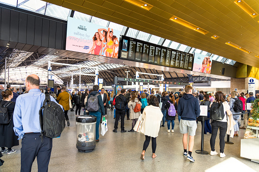 Glasgow, Scotland - People in Queen Street station in central Glasgow, with the main information board displaying details of train arrivals and departures.