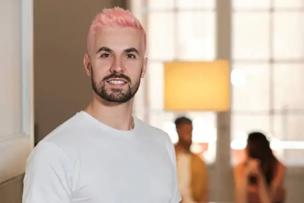 front view of a smiling person with a pink dyed hair in a cozy space