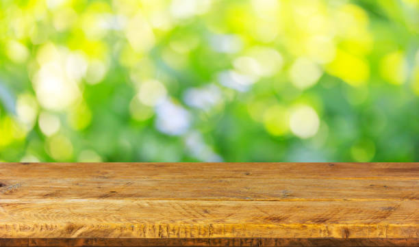 istock Empty wood table top on natural green background with bokeh. Mock up for display product. 1398340347