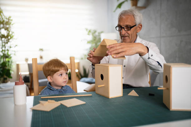 istock Senior man making a birdhouse, while his toddler grandson observing him 1398341471
