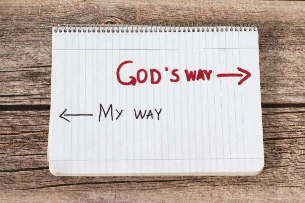 God's way, a handwritten text quote and arrows in a white notebook page placed on a wooden background stock photo