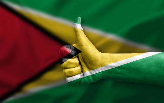 Hand making thumb up painted with flag of guyana