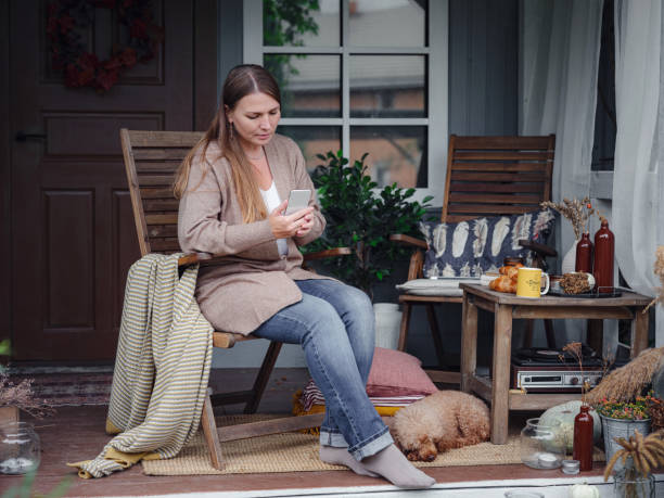 Thoughtful, urban, modern, blond woman in caftan having coffee, sitting alone in a lovely shabby chic style backyard.