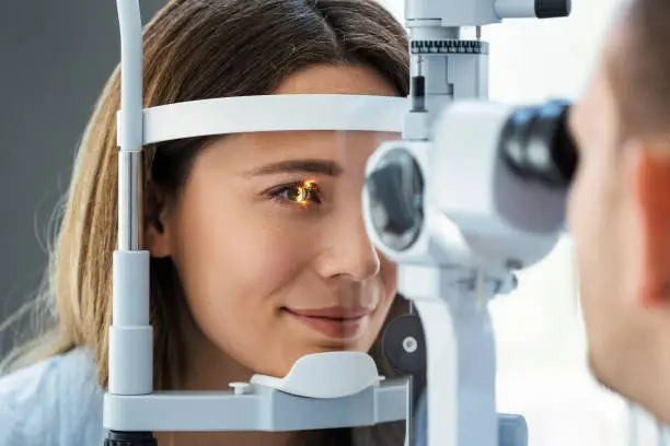 Photo of Beautiful young girl checking the eye vision in ophthalmology clinic