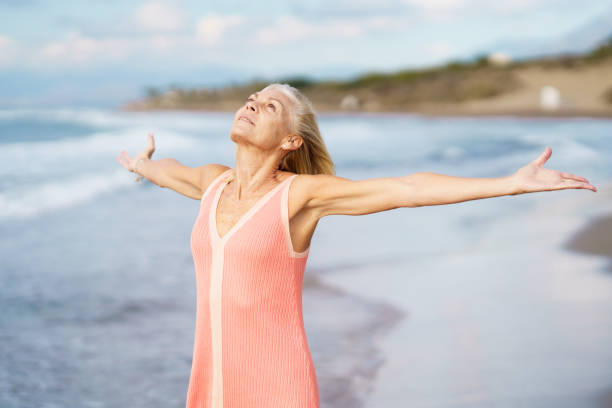 istock Elderly woman enjoying freedom at seaside 1398352668