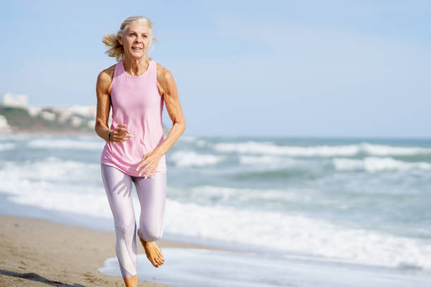 istock Elderly sportswoman running along seashore in summer 1398352895